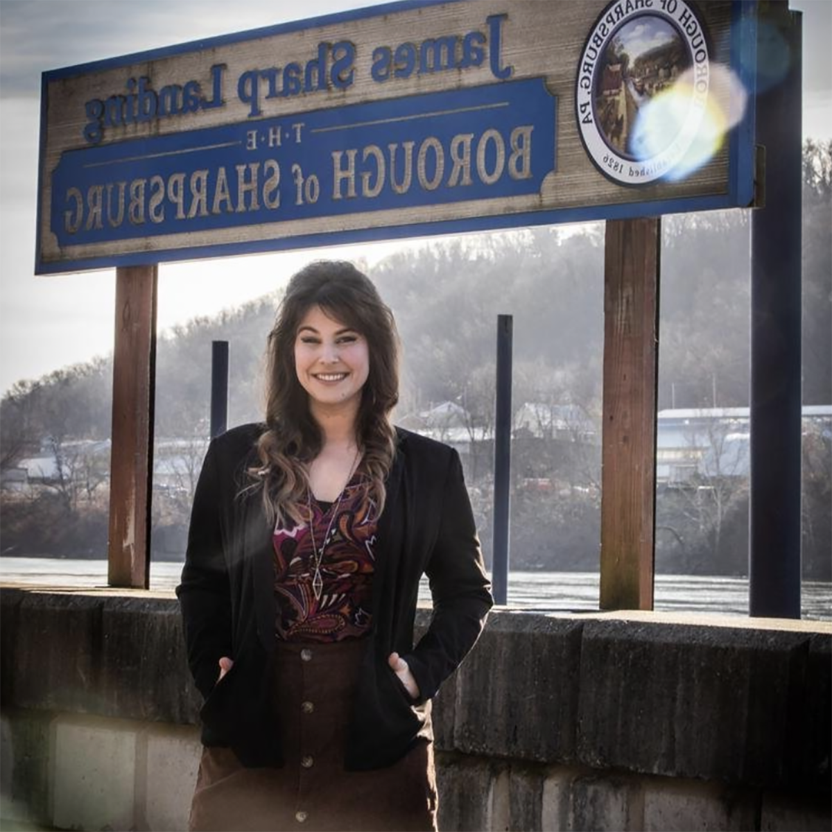 Photo of Brittany Reno, Mayor of Sharpsburg, posing in front of the town boundary sign