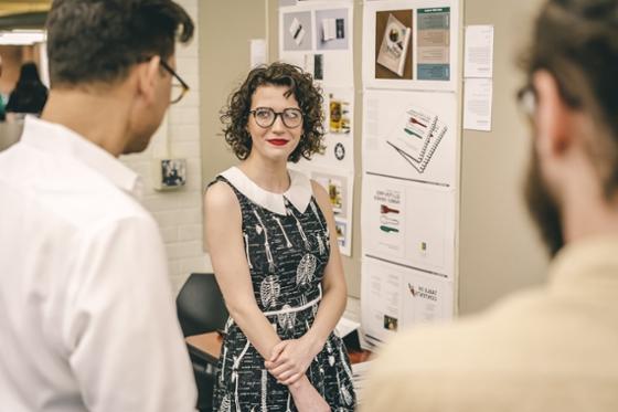 Photo of a smiling Chatham University student presenting her work to students and a professor